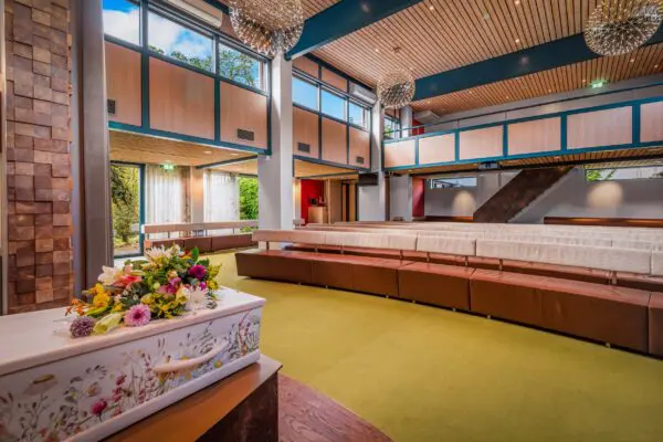 Kist met bloemstuk voor de gebogen zitbanken in ceremonieruimte Campherbeek.