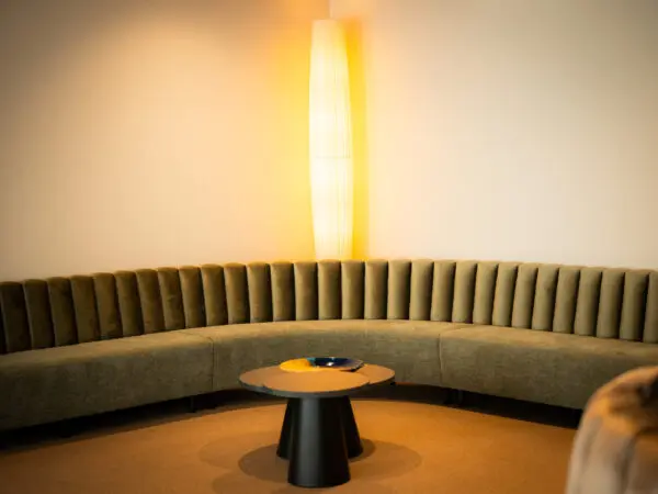 Gebogen zitbank met een ronde tafel en wandlamp in de familiekamer.