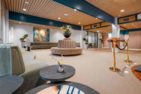 Ruime ontvangsthal met een houten plafond, zitplaatsen en een ronde tafel.