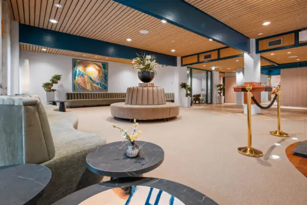 Ruime ontvangsthal met een houten plafond, zitplaatsen en een ronde tafel.