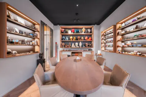 Toonkamer met een ovale tafel en verlichte kasten met verschillende urnen.