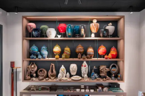 Wandkast met verschillende urnen en persoonlijke gedenkobjecten in de toonkamer.
