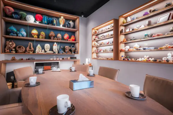 Toonkamer van Crematorium Kranenburg met een houten tafel en wandkasten met urnen en gedenkobjecten.