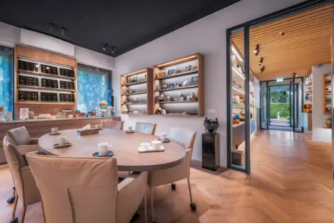 Ovale tafel in de toonkamer met wandkasten vol urnen en gedenkobjecten.