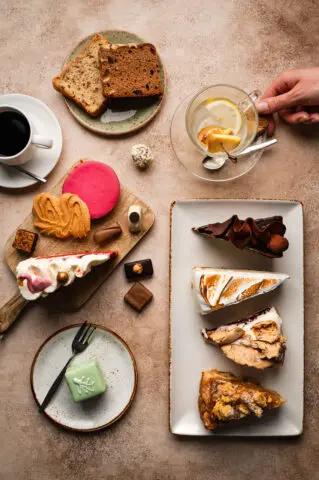 Tafel met verschillende soorten gebak, koekjes, koffie en thee.
