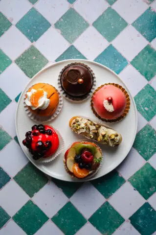 Bord met verschillende kleine gebakjes en zoetigheden op een geruit tafelkleed.